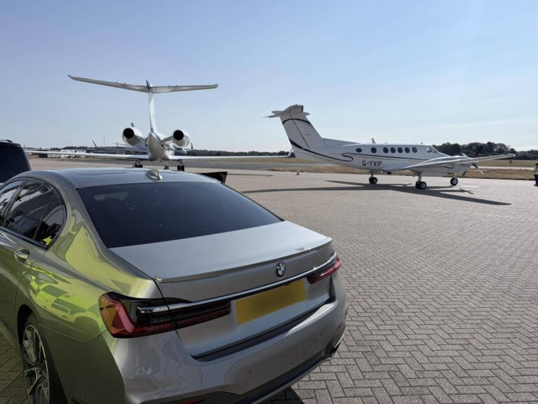 BMW 7 Series chauffeur car parked beside private jets at an airfield