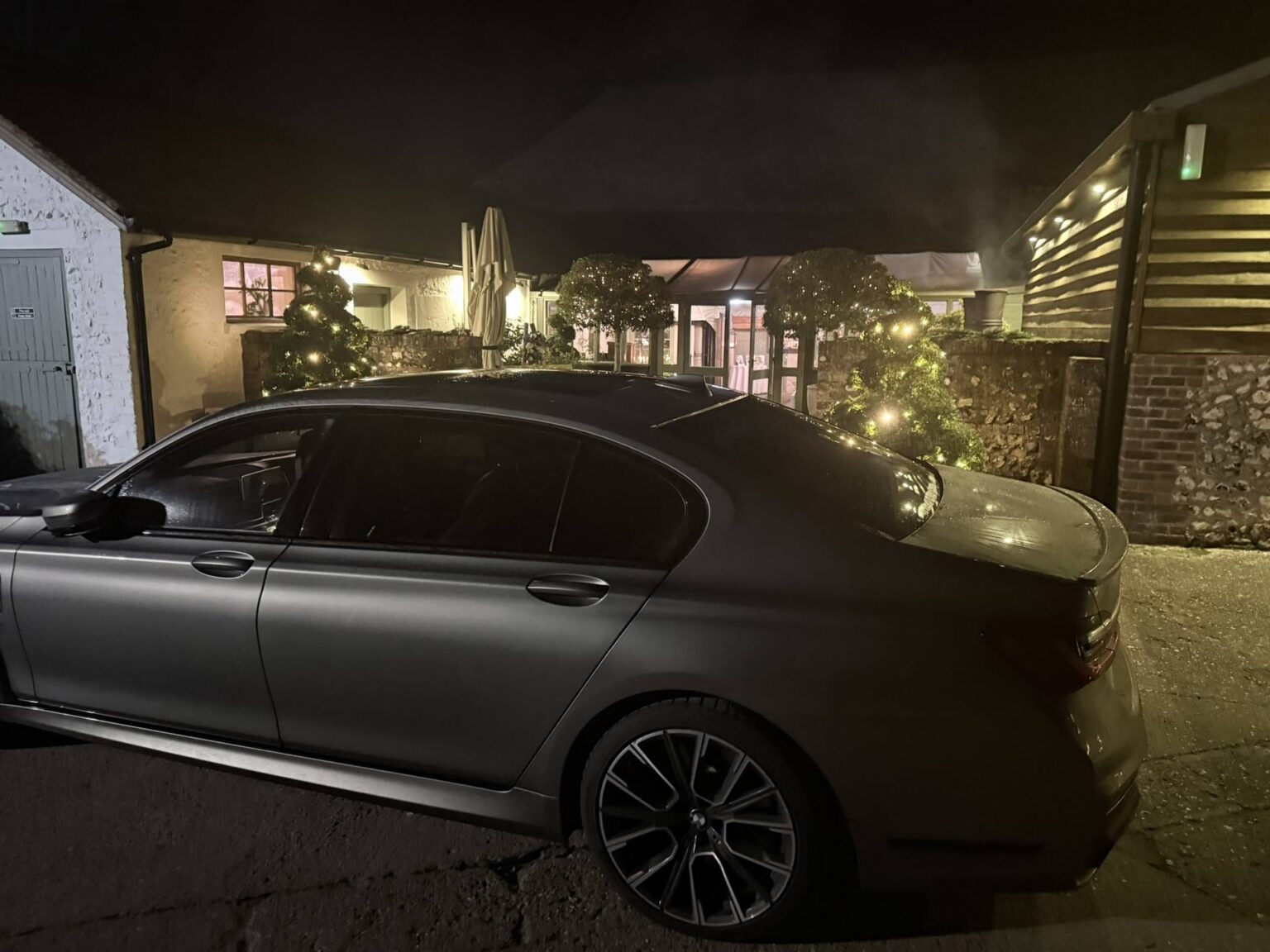 BMW 7 Series chauffeur car at night outside a country pub with fairy lights