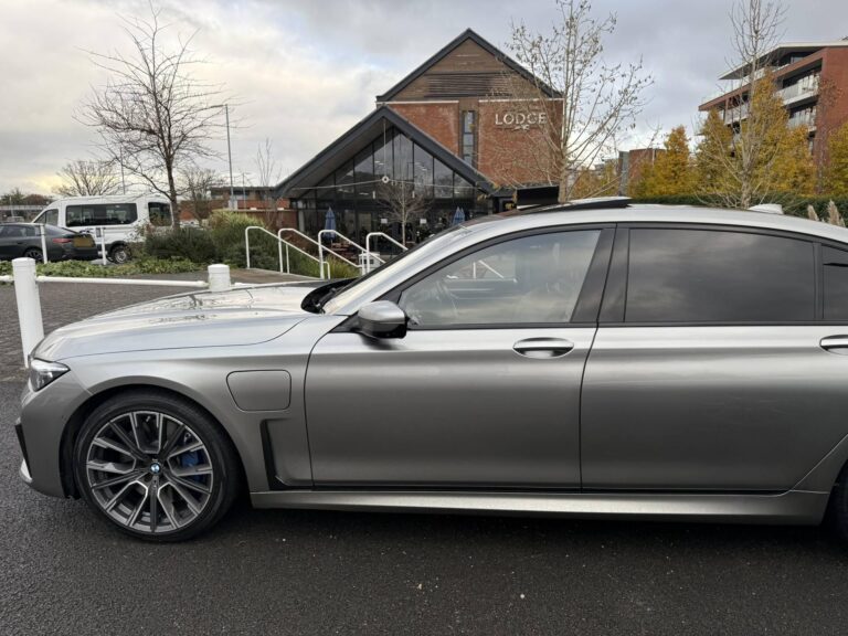 Grey BMW 7 Series chauffeur car, side view, parked outside a hotel