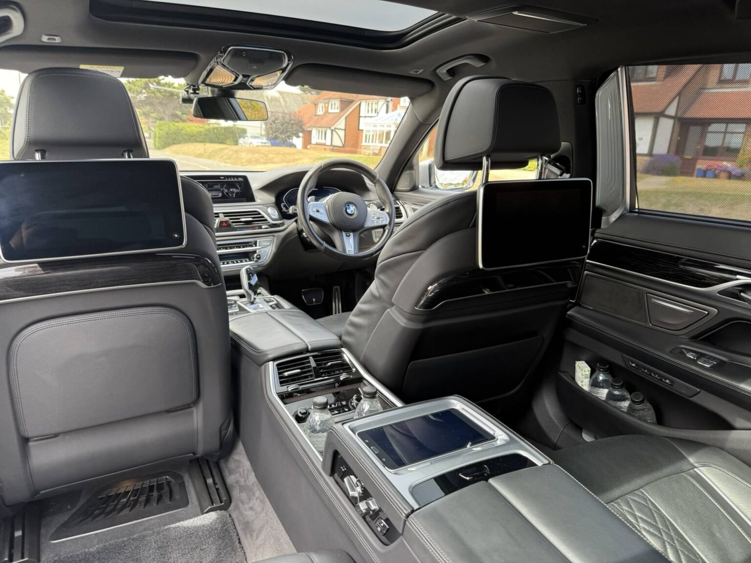 Rear cabin of a BMW 7 Series chauffeur car, with seat-back screens and leather seats