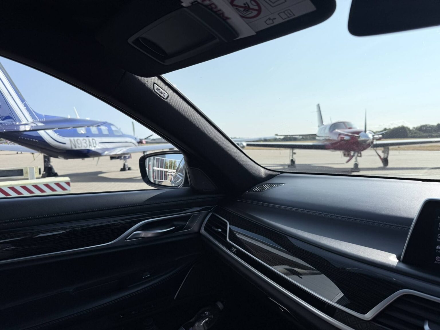 Private jets on an airfield seen through the window of a BMW 7 Series chauffeur car