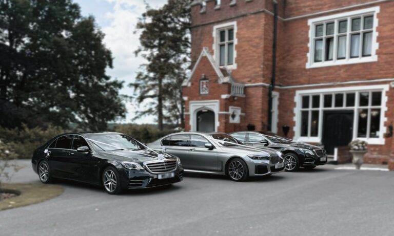 Three chauffeur-driven cars, the lead car dressed with wedding ribbons, outside a wedding venue