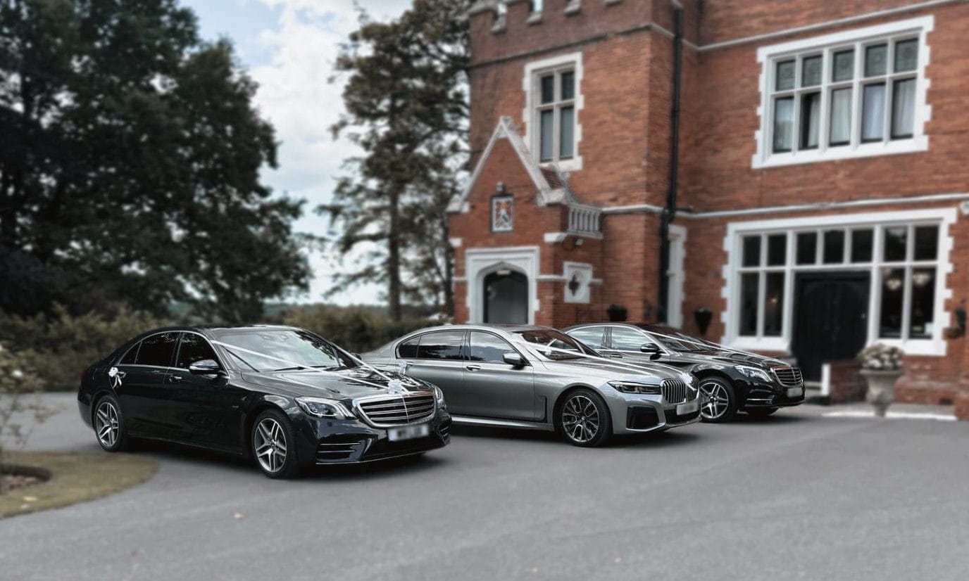 Three chauffeur-driven cars, the lead car dressed with wedding ribbons